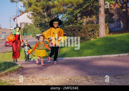 Familien mit Kindern gehen in Halloween-Kostümen, Eimer halten Stockfoto