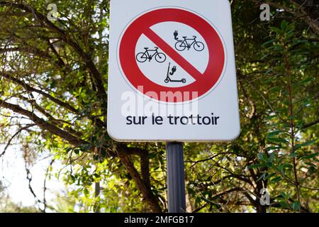 Verbotsschild mit französischem Text sur le trottoir bedeutet auf dem Gehweg Elektrofahrzeuge Fahrrad-Roller verboten Stockfoto