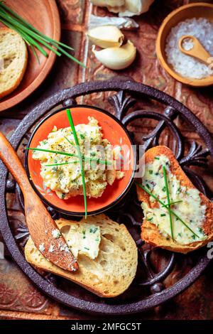 Hausgemachtes Knoblauchbrot oder Baguettscheiben mit Knoblauchbutter und Kräutern auf dem Küchentisch Stockfoto