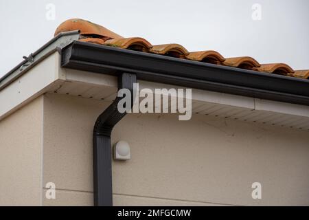 Metallrinne in Schwarz auf dem Dach mit Keramikfliesen Nahaufnahme Stockfoto