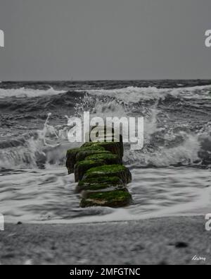 Ein vertikaler Langzeitaufnahme von Wellen, die an einem düsteren Tag in die Steingärten der Ostsee stürzen Stockfoto