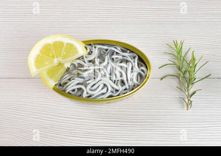 Aus einem hohen Winkel, eine köstliche Dose Aal auf einem rustikalen Holztisch mit Zitrone Stockfoto