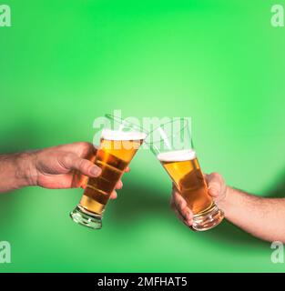 Zwei sanfte Männer mit Gläsern Bier, die auf grünem Hintergrund toasten Stockfoto