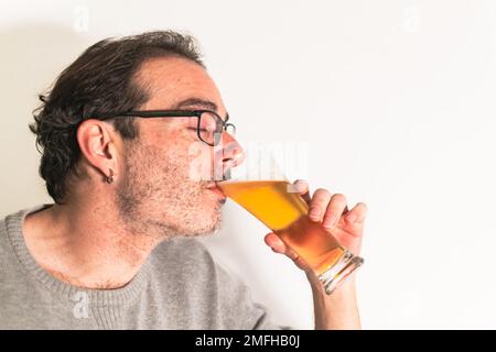 Ein Mann trinkt ein Glas Bier mit geschlossenen Augen und genießt den Moment. Stockfoto