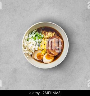 Asiatische Nudelsuppe, Ramen mit Fleisch, Tofu, Gemüse, Enoki-Pilze und Ei in schwarzer Schüssel Stockfoto