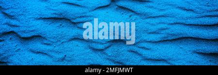Abstrakter welliger sandiger Hintergrund. Sandtextur in der Wüste oder am Strand. Horizontales Banner - Blautöne Stockfoto