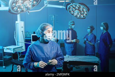 Chirurg's Assistenztechniker steht im Operationssaal des Krankenhauses mit ihren medizinischen Kollegen. Porträt der Chirurgischen Krankenschwester Stockfoto