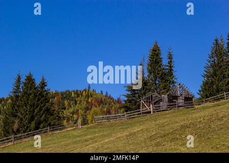 Ein altes, verlassenes Bauernhaus auf einer Bergwiese über den Karpaten. Wunderschöne Wanderlandschaft in der Ukraine. Herbstzeit. Stockfoto