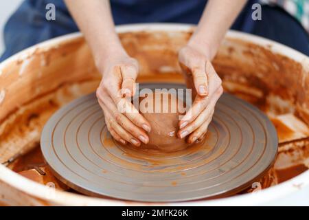 Zugeschnittenes Bild eines nicht wiedererkennbaren weiblichen Keramikherstellers, der mit Ton auf Töpferrad in Cozy Workshop, Creative People Handcraft Pottery Class arbeitet. Stockfoto