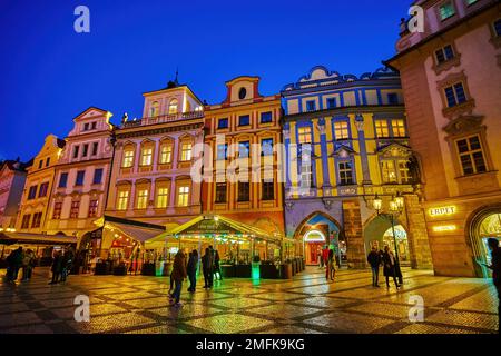 PRAG, TSCHECHIEN - 11. MÄRZ 2022: Farbenfrohe mittelalterliche Stadthäuser auf dem Altstädter Ring mit Restaurants im Erdgeschoss in heller Beleuchtung, Stockfoto