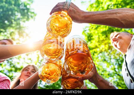 Eine Gruppe glücklicher bayerischer Freunde, die Bier trinken und anstoßen beim Oktoberfest, Folk- oder Bierfestival in deutschland Stockfoto