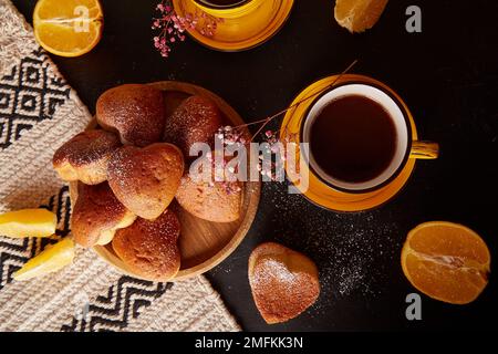 Ästhetische, hausgemachte herzförmige Muffins mit Orangengeschmack für Valentinstag-Flat Lay. Teezeit-Ästhetik. Stockfoto