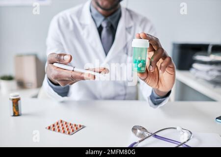 Nahaufnahme eines nicht wiedererkennbaren afroamerikanischen Arztes, der eine Flasche Pillen in die Kamera hält und zeigt Stockfoto