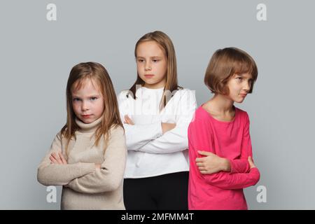 Drei aufgebrachte Kinder, Freunde, die mit gekreuzten Armen stehen. Junge Mädchen, 8-10 Jahre alt Stockfoto