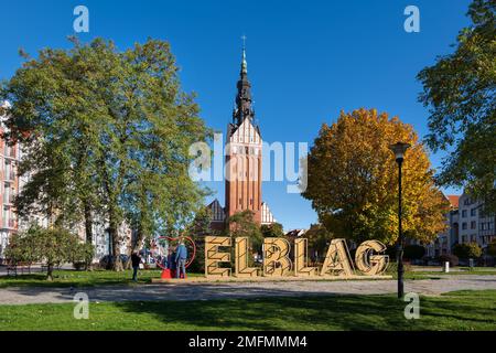 Elblag, Polen - 10. Oktober 2022 - Willkommensschild der Stadt und gotischer Turm von St. Nicholas Kathedrale in der Altstadt Stockfoto