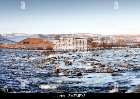 Zusammenfluss von River Tees und Harwood Beck mit dem Old Farmstead of Wheysike House Beyond in Winter, Forest-in-Teesdale, County Durham, Großbritannien Stockfoto