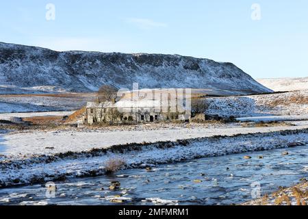 Die imposanten Felsen von Cronkley Fell und der alte Bauernhof des Wheysike House blickten über Harwood Beck vom Pennine Way im Winter, Forest-in-Teesd Stockfoto