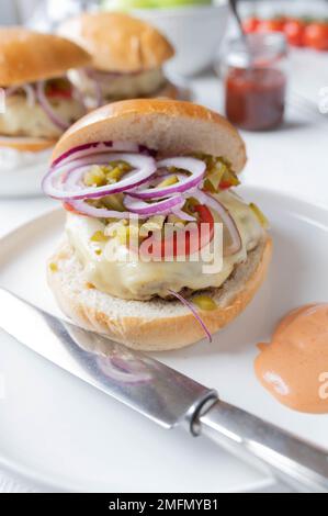 Hausgemachter Hamburger mit Käse, Zwiebeln, Gurken, Tomaten und Burgersauce Stockfoto