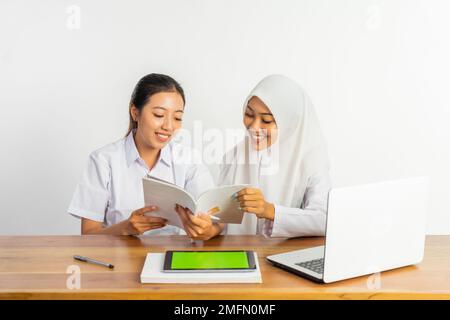 Zwei Highschool-Mädchen, die am Schreibtisch sitzen und Bücher lesen Stockfoto