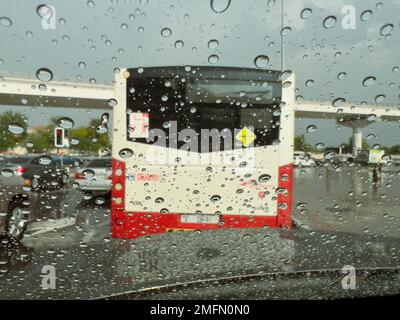 Selektiver Fokus und Bewegungsunschärfe von Regentropfen auf der Windschutzscheibe eines Fahrzeugs im Verkehr während eines Regengusses in Dubai, vereinigen Sie die Arabischen Emirate. Stockfoto