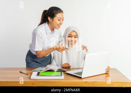 Zwei Highschool-Mädchen, die am Schreibtisch sitzen und ihren Laptop benutzen Stockfoto