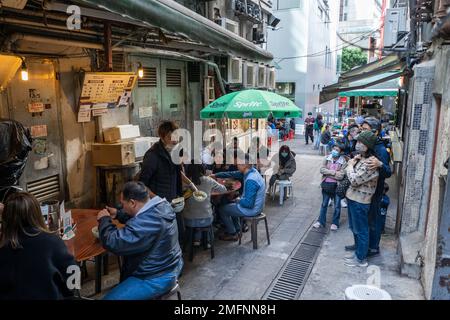 Hongkong - 2022. Dezember - Menschen, die an einem Imbissstand im Central District essen Stockfoto