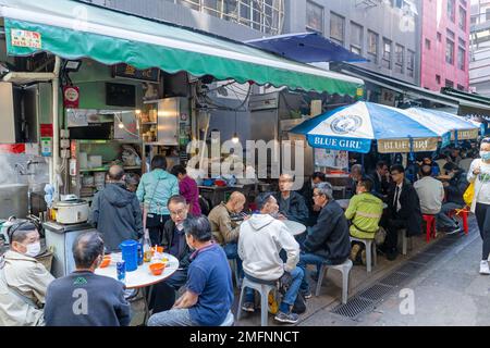 Hongkong - 2022. Dezember - Menschen, die an einem Imbissstand im Central District essen Stockfoto