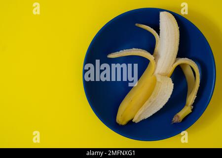 Halb geschälte Banane auf dunkelblauem Teller Stockfoto