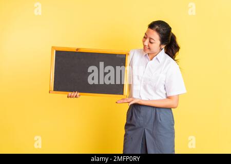 Ein Mädchen in Uniform, das neben ihr eine Tafel hält und sie ansieht Stockfoto