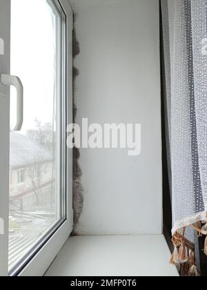 Schwarzer Schimmel und Pilz an der Wand in der Nähe des Fensters. Das Problem der Belüftung, Feuchtigkeit, Kälte in der Wohnung Stockfoto