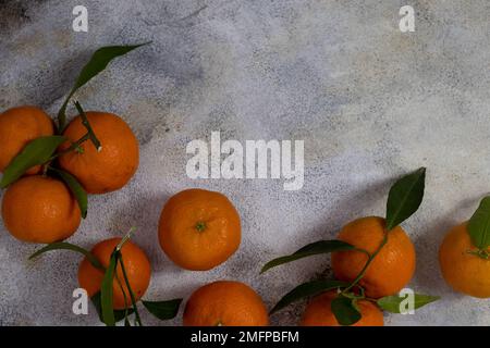 Frische Tangerinen mit grünen Blättern auf hellem Hintergrund Stockfoto