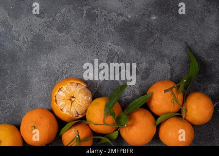 Mandarinen mit grünen Blättern auf dunklem Grund Stockfoto