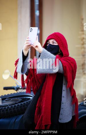 Frau mit traditioneller Winterkleidung und Schutzmaske geht durch die Straßen von Lissabon Stockfoto
