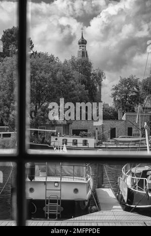 Enkhuizen, Niederlande - August 18,2021: Blick aus dem Fenster auf den Hafen und festgemachte Segelboote. Im Hintergrund die Kuppel der Kirche und Stunni Stockfoto