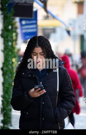 Frau mit Smartphone in der Hand spaziert durch die Straßen von Lissabon Stockfoto