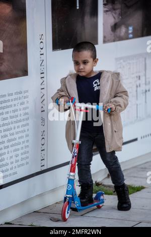 Kind auf dem Roller durch die Straßen der Stadt Stockfoto