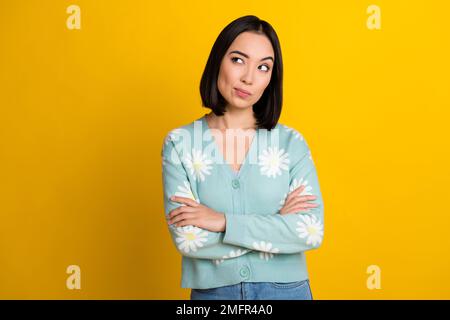 Porträtfoto-Kadre eines verdächtigen chinesischen Mädchens gefaltete Arme, die leer aussehen Tragen Sie einen Pullover mit Gänseblümchenmuster isoliert auf gelbem Hintergrund Stockfoto