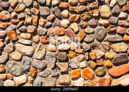 Die Oberfläche besteht aus altem, mehrfarbigem Stein. Hintergrund verschiedener Steinformen. Stockfoto