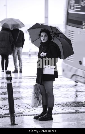 Ein Mädchen läuft mit einem Schirm durch die Straßen von Lissabon Stockfoto