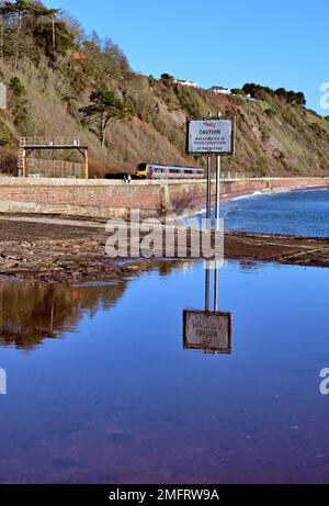 Ein Skilanglauf entlang der Ufermauer zwischen Hole Head (Parsons Tunnel) und Sprey Point, wo ein Warnhinweis in einer großen Pfütze reflektiert wird. Stockfoto