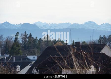 Blick von den Dächern des Wohnviertels in einer Schweizer Stadt Hinwil, umgeben von Alpenbergen bei Sonnenuntergang. Stockfoto