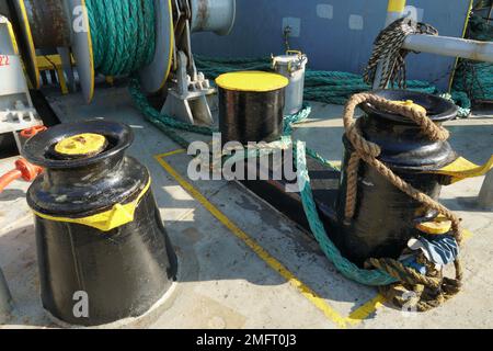 Nahaufnahme auf schwarz-gelb lackierten Pollern und Festmacherwalze in der vorderen Manövrierstation auf einem Containerschiff. Stockfoto