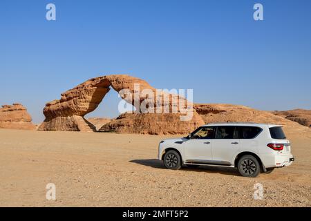 Auto vor dem Arch, auch bekannt als Rainbow Rock, in der Nähe von Alula, Medina Province, Saudi-Arabien, Arabische Halbinsel Stockfoto