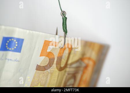 Nahaufnahme eines 50-Euro-Scheins, der an einen Angelhaken gekoppelt ist, isoliert auf weißem Hintergrund Stockfoto