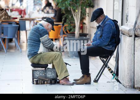 Ein älterer Mann putzt seine Schuhe auf der Straße Stockfoto