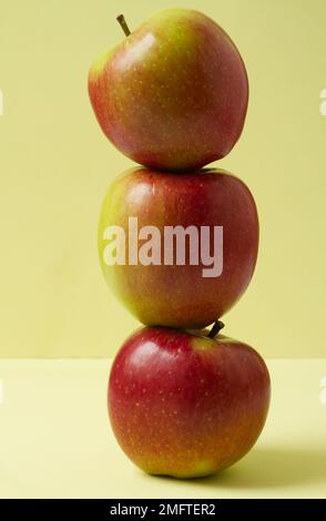 Nahaufnahme von drei Braeburn-Äpfeln, die übereinander gestapelt sind, vor einem einfachen Hintergrund Stockfoto