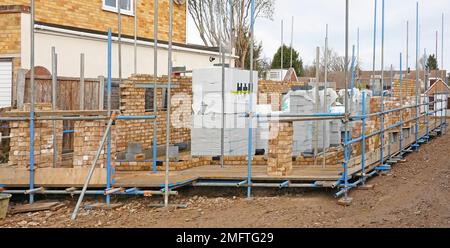 Blick von der Vorderseite aus neue Ziegel- und Blockwände werden für freistehende Wohngrundgerüste errichtet Baumaterialien gestapelt England Großbritannien Stockfoto