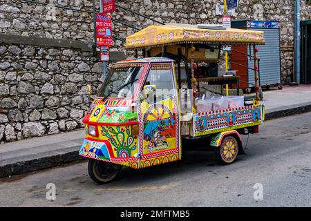 Farbenfroh dekorierter kleiner Lieferwagen Piaggio Ape, der Süßigkeiten im alten Teil des Touristenziels Taormina verkauft. Stockfoto