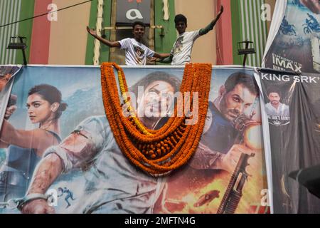 Vor der Veröffentlichung von Pathaan in Kalkutta, Indien, haben Fans vor einem Kino ein Poster von Sharukh Khan gekleidet. Am 25. Januar 2023 kehrte Sharukh Khan nach 4 Jahren mit der Veröffentlichung des Films "Pathaan", der vor seiner Veröffentlichung das Licht der Kontroverse erblickte, auf die große Leinwand zurück. Vishwa Hindu Parishad und Bajrang Dal haben wegen Kontroversen um ein Lied des Films, das die Schauspielerin in Saffronkleidung zeigt, einen Boykott des Films gefordert, der laut Demonstranten die Gefühle vieler rechter Aktivisten verletzt hat. Inmitten des Protests blieb der Verstand nach dem Film unberührt Stockfoto