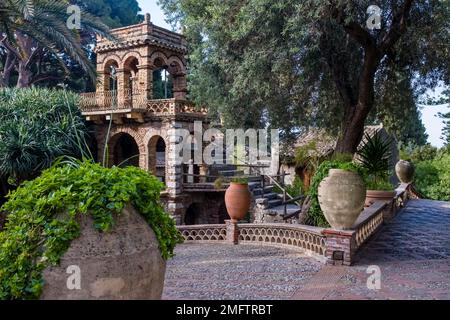 Fantasievolle Gebäude und wunderschöne Plantagen im Parco Florence Trevelyan, einer der wichtigsten Sehenswürdigkeiten des Touristenziels Taormina. Stockfoto